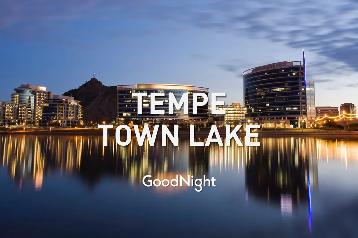 A tranquil scene of Tempe Town Lake with modern buildings reflecting off the calm water. The lakeside path and open space suggest opportunities for peaceful walks, outdoor relaxation, and connecting with the local environment.