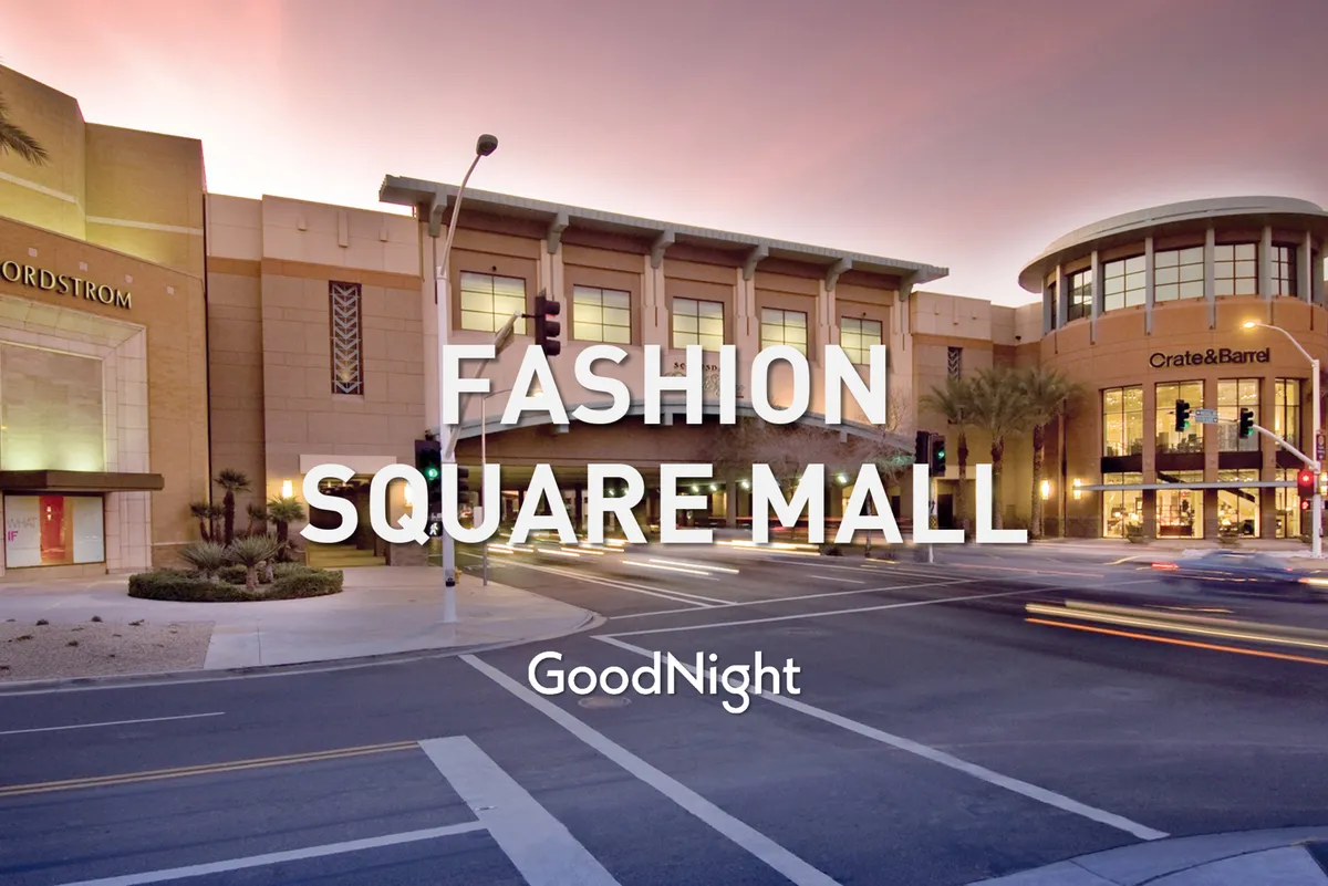 An energetic exterior shot featuring the recognizable storefronts of Nordstrom and Crate & Barrel at Kierland Commons, framed by palm trees and sunset lighting. There is visible movement and vibrancy, suggesting a lively shopping and dining district just minutes from the property.