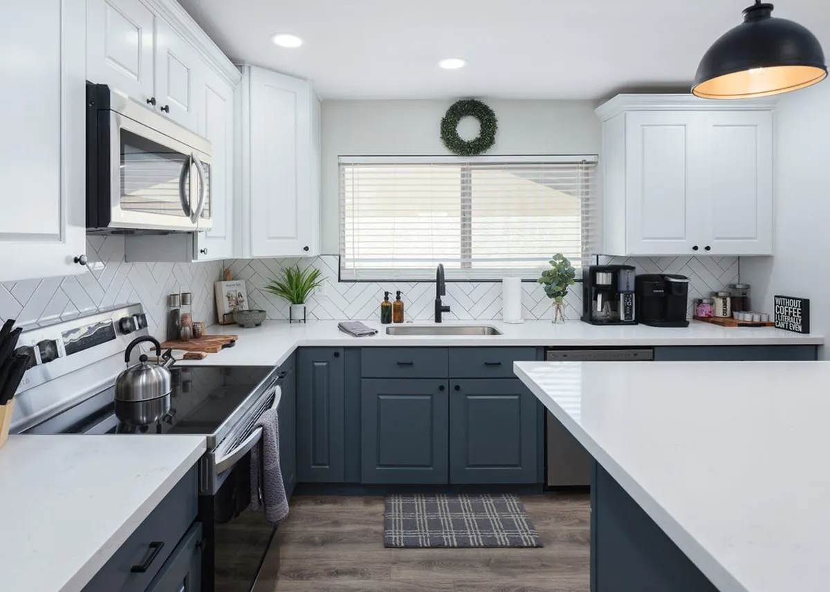 A bright, airy kitchen with a large island, modern stainless steel appliances, a window streaming in natural light, a decorative plant, and a dedicated coffee station. The space feels welcoming, ideal for both meal prep and casual coffee breaks.