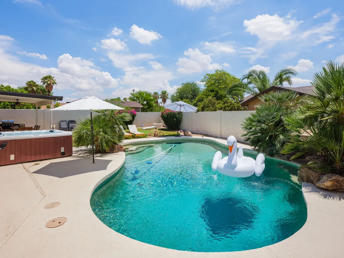 This image features a private swimming pool complete with a playful inflatable swan, a jacuzzi, sun loungers, and umbrellas. The setting is lively and inviting, suggesting a space perfect for family fun, relaxation, and social gatherings.